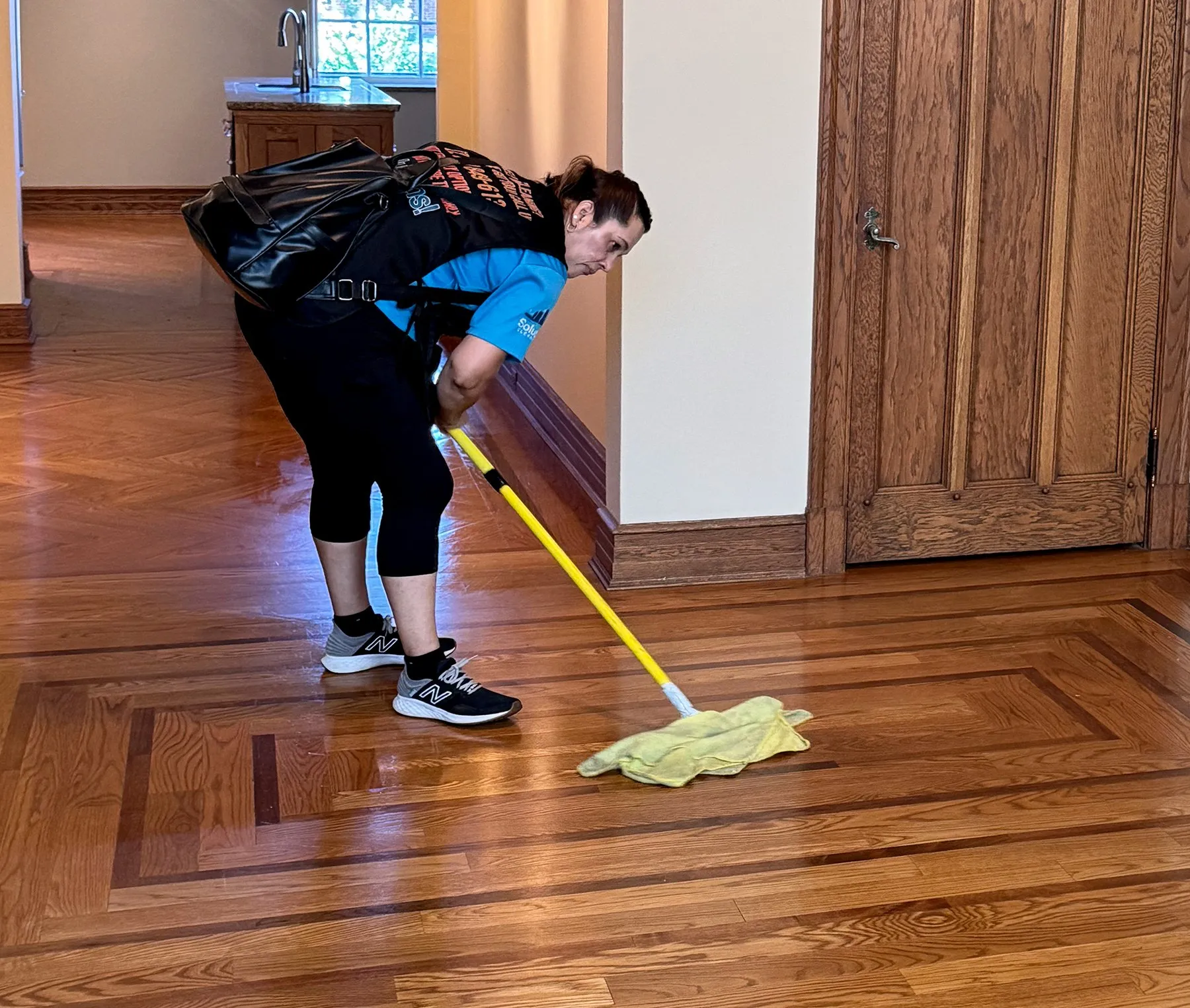 Solutions Cleaning technician mopping a hardwood floor